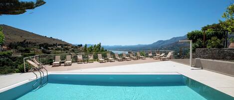 A pool with lounge chairs and a view of the mountains.