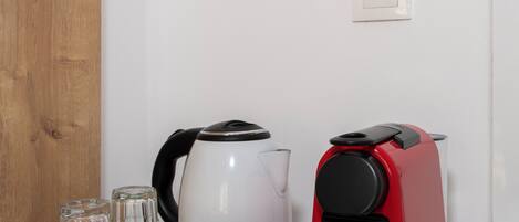 A kitchen with a coffee maker, a kettle, and a bowl on a tray.