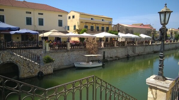 Un restaurante a orillas de un canal, con terraza, paredes de piedra y un bote.