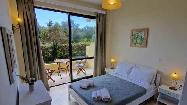 A bedroom with a bed, bedside tables, a desk, and a window with curtains.