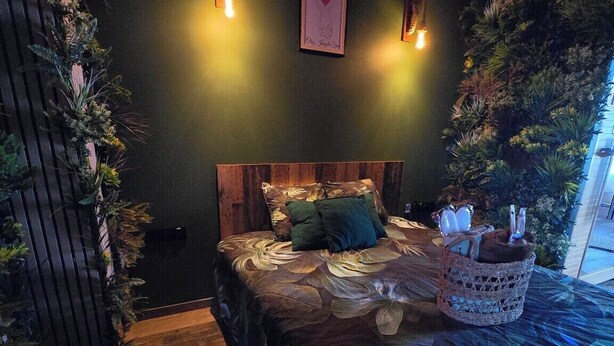 Una camera da letto con testiera in legno, un letto con biancheria a motivi, un condizionatore d'aria a parete e un quadro incorniciato.