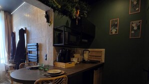 Un'accogliente zona pranzo con un tavolo rotondo e sedie in vimini, un forno a microonde e un angolo cottura con un bancone e pensili.