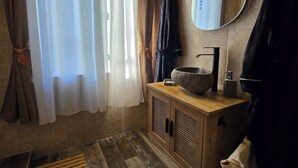 Un bagno con un mobile lavabo in legno, una bacinella in pietra, uno specchio e un porta asciugamani.