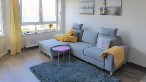Una sala de estar moderna con un sofá gris, una mesita auxiliar y un tapete azul.