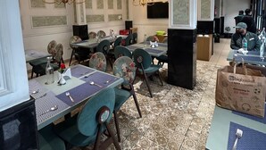 Un espace repas comprenant plusieurs tables et chaises, un lustre et un plafond orné de motifs.
