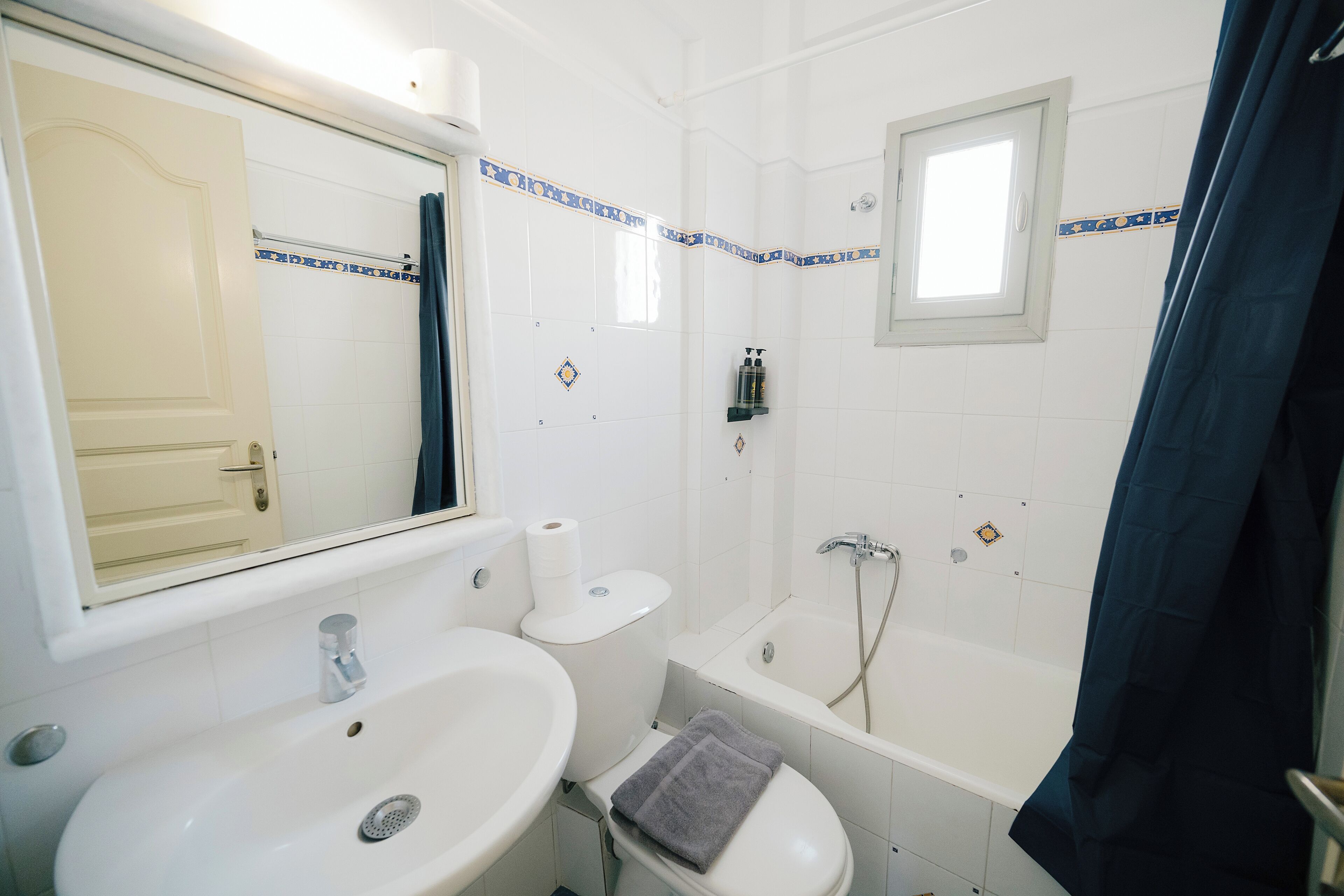 A bathroom with a sink, toilet, bathtub, and a window.
