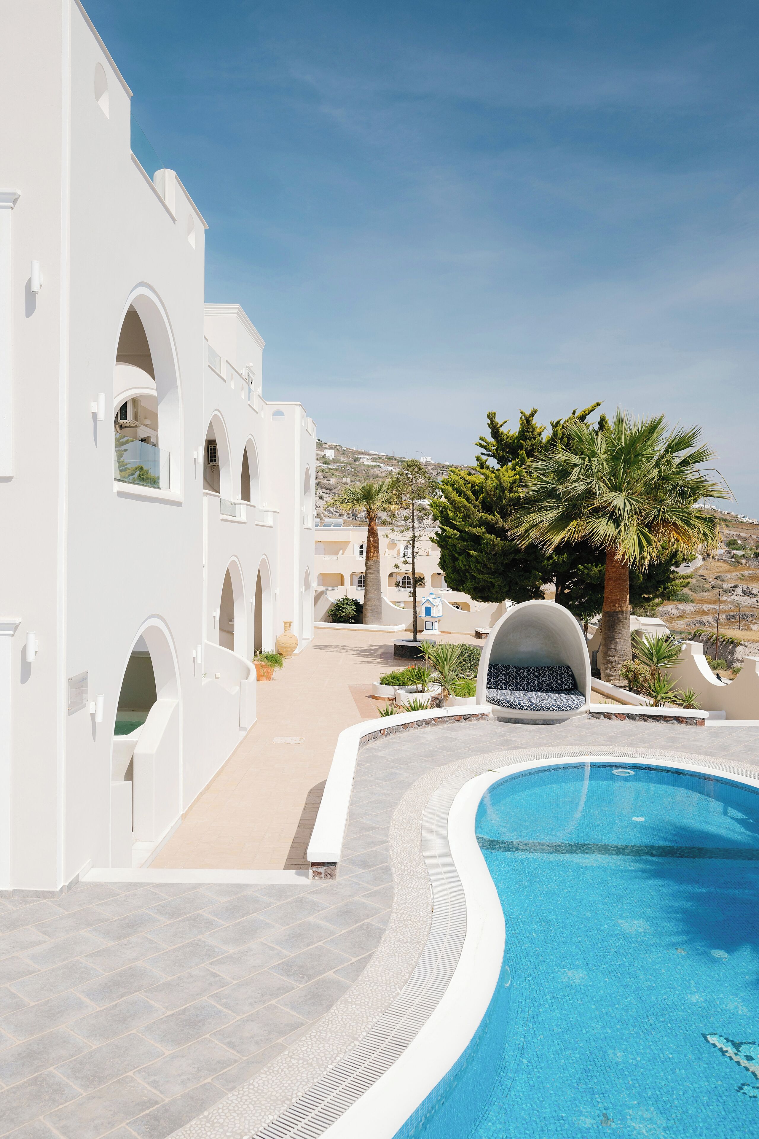 Un edificio bianco con finestre ad arco, una piscina e palme.