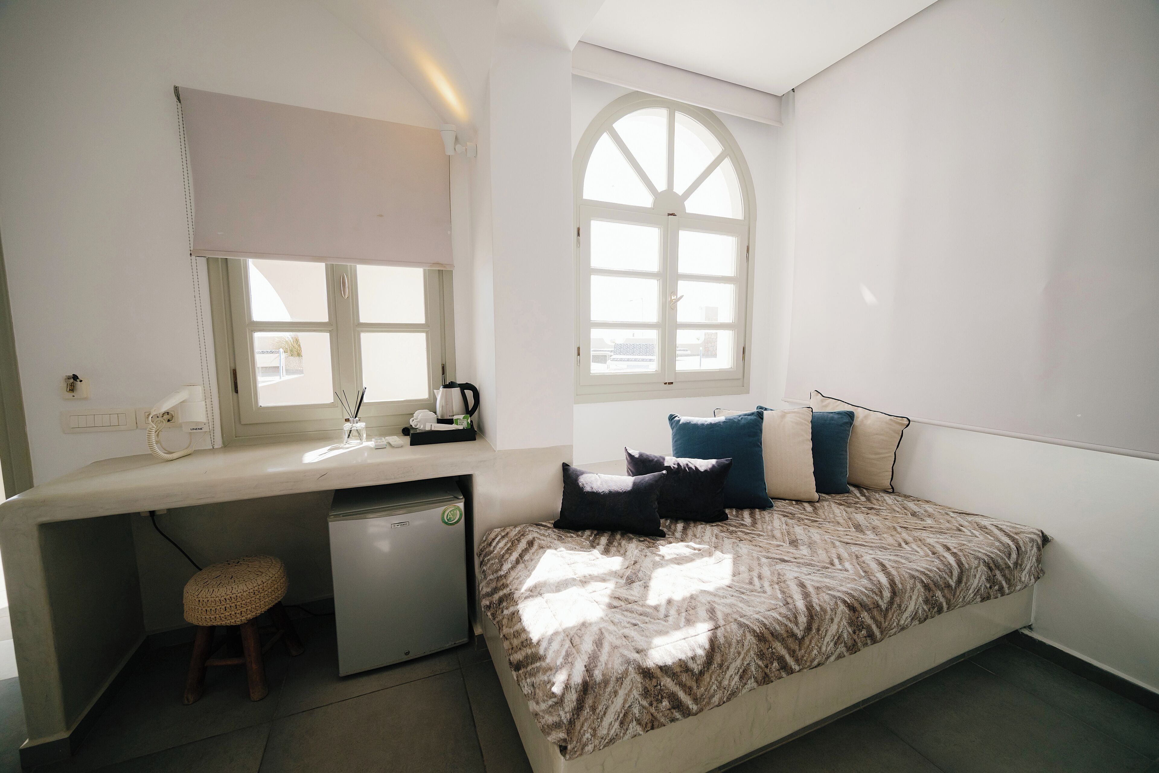 Ein gemütlicher Raum mit Bett, Schreibtisch, kleinem Kühlschrank und Fenster mit Blick.