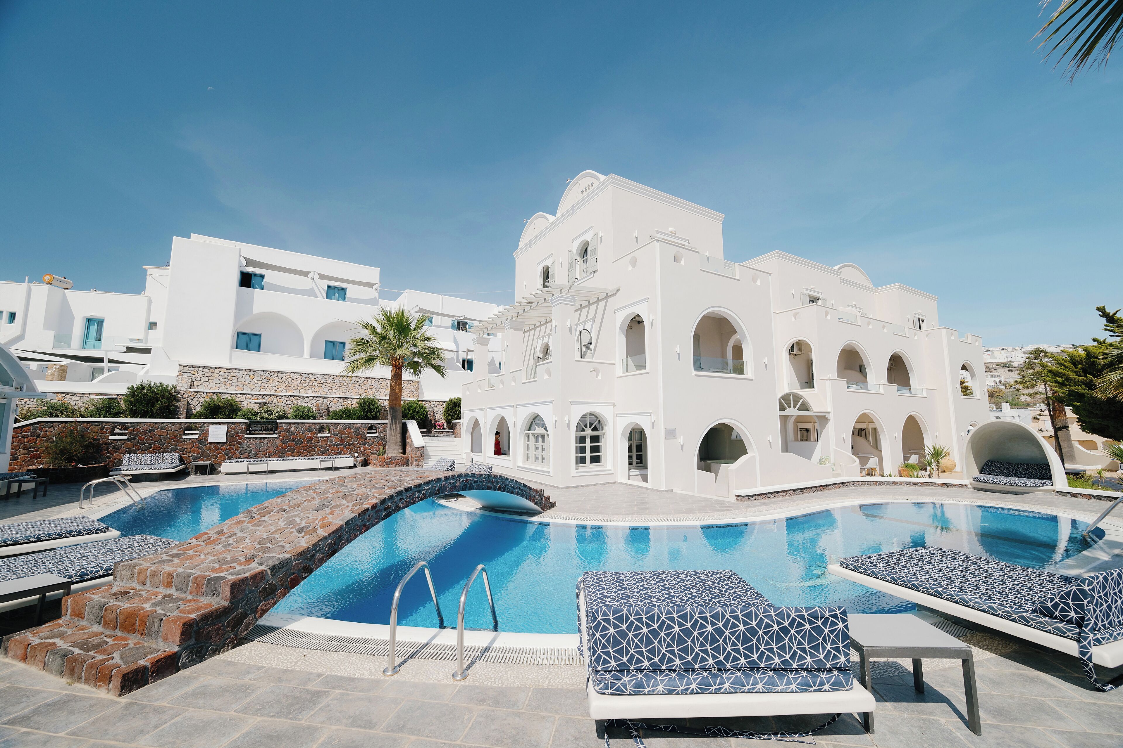 Ein Pool mit Liegestühlen und ein weißes Gebäude mit Bögen.