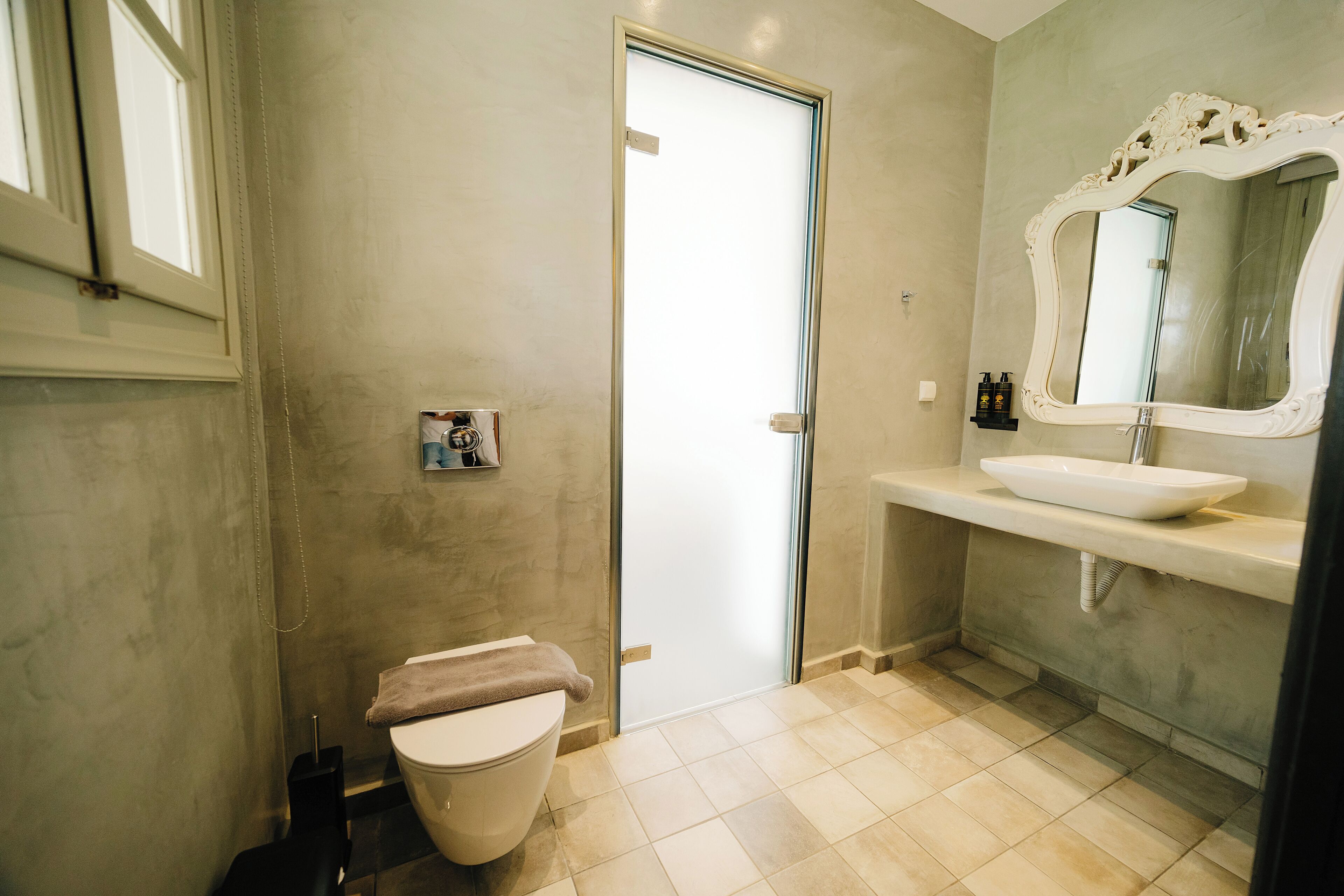 A bathroom with a toilet, a sink, a mirror, and a shower area.