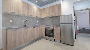 A modern kitchen with wooden cabinets, a stainless steel refrigerator, a built-in oven, and a sink with a faucet. - Mpia House by RentalsPro (Nea Moudania)