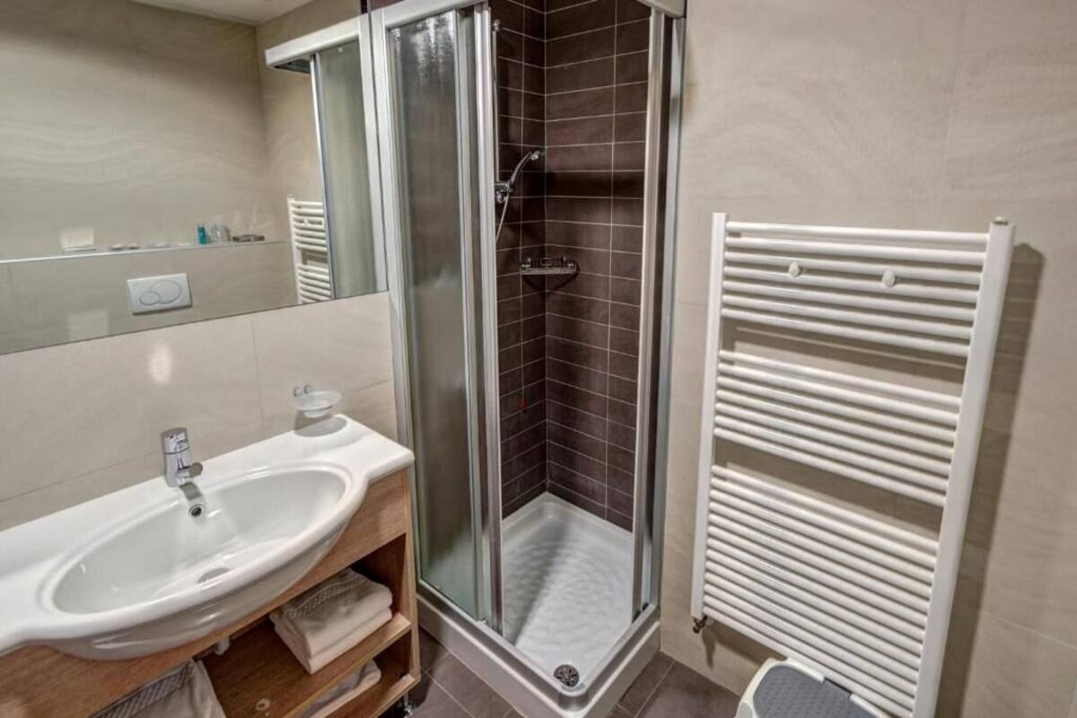 A modern bathroom with a shower enclosure, a sink, and a towel rack.