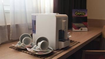 Una camera d'albergo con una macchina per il caffè, due tazze e un cartello con la scritta Hotel Capital.