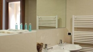 A bathroom with two sinks, a mirror, and a towel rack. - HOTEL CAPITAL (Rovigo)
