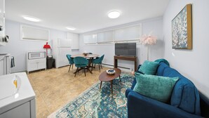 Un espacio habitable compacto con kitchenette, comedor y sofá sobre un tapete estampado.