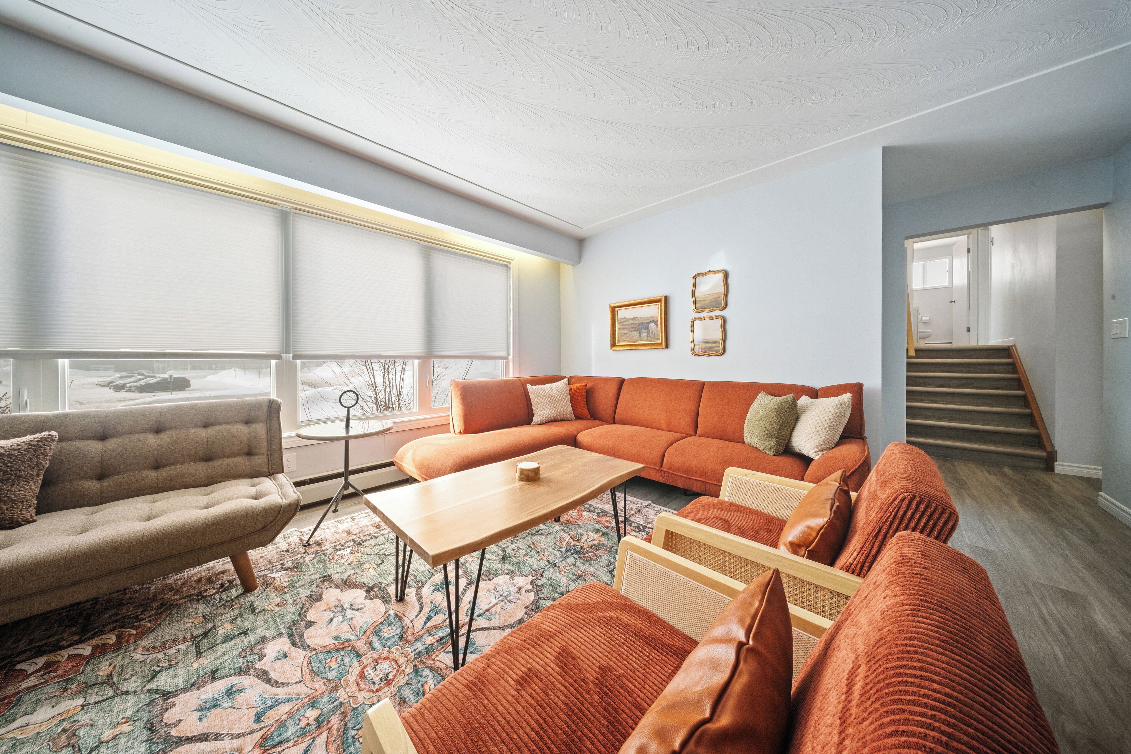 Un salon moderne avec un canapé d’angle, une table basse et un tapis à motifs.