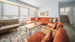 A modern living room with a sectional sofa, a coffee table, and a patterned rug.