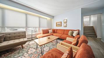 Un salon moderne avec un canapé d’angle, une table basse et un tapis à motifs.