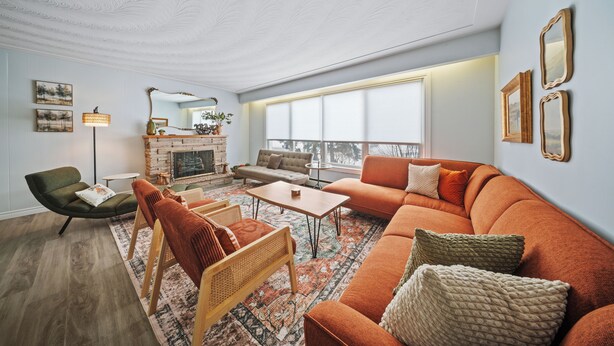 A modern living room with a sofa, armchairs, a coffee table, and a fireplace.