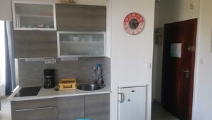 A compact kitchen with a built-in oven, a sink, and a small refrigerator. - T2 less than 50m from the beach in Beg Meil near Fouesnant (Fouesnant)