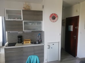 Eine kompakte Küche mit Backofen, Spüle und kleinem Kühlschrank.