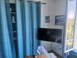 Ein Zimmer mit großem Fenster, einem an der Wand befestigten Flachbildfernseher, einer Ablage mit Dekoration und einer Wand mit Wandgemälde einer Schildkröte.