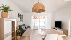 A modern living room with a dining area, a sofa, a TV, and a large window. - Casa Da Roca Medano - Beach House & Terrace (Granadilla de Abona)