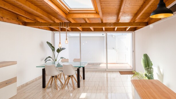 A modern kitchen with wooden beams, a glass table, and chairs. - Casa Da Roca Medano - Beach House & Terrace (Granadilla de Abona)