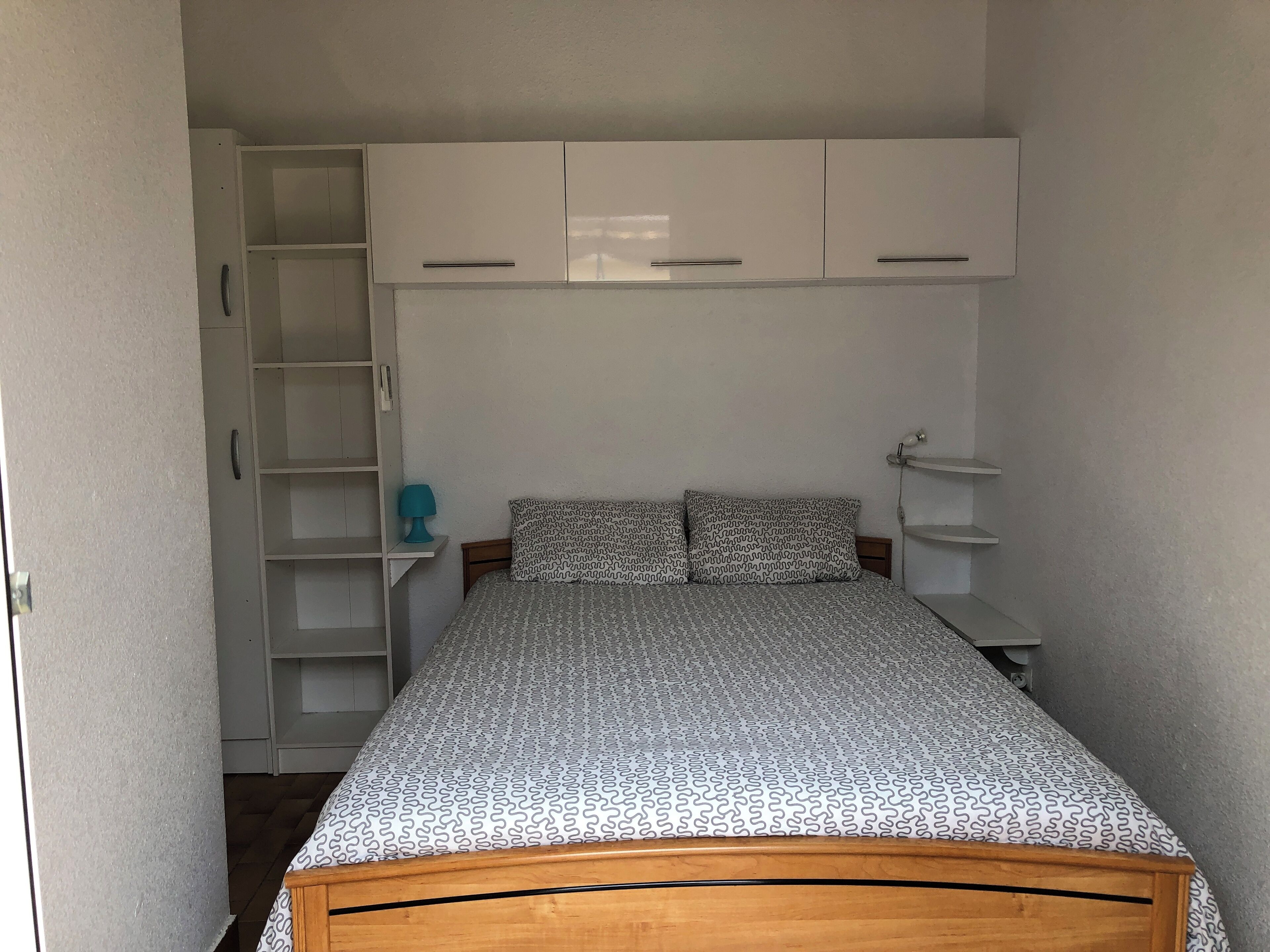 Une chambre à coucher avec un lit, une literie à motifs, une armoire et une table de chevet.