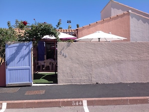 A gated entrance with a blue door, a small patio area with a table and chairs, and a textured wall with the number 544. - Pretty villa with swimming pool (Canet-en-Roussillon)
