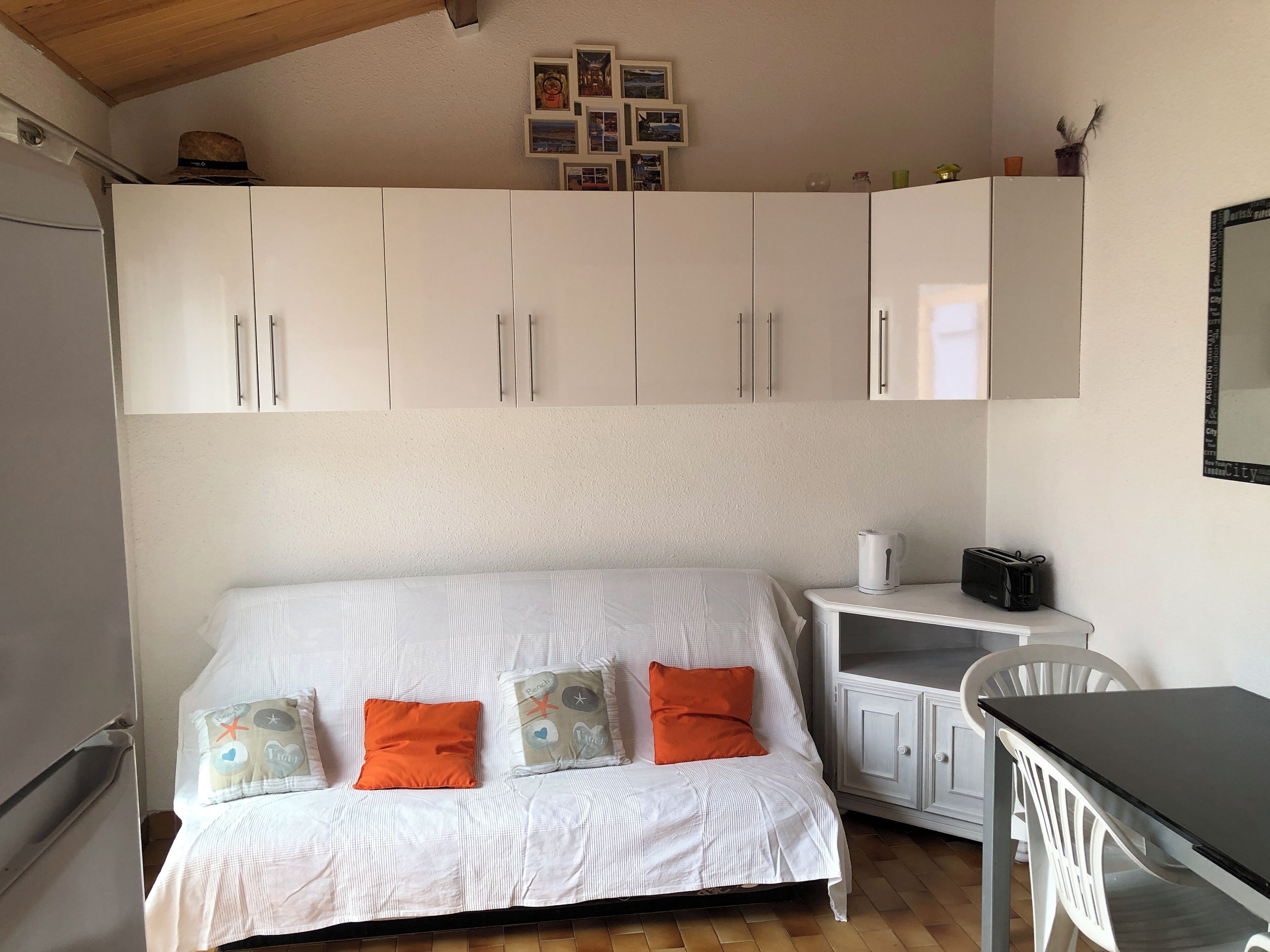 A bedroom with a bed, a small table, and a white wardrobe.