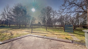 A fenced outdoor area with a gravel path, trees, and a blue gate. - Maison 4ch avec cheminée, billard et jardin (Saint-Evroult-Notre-Dame-du-Bois)