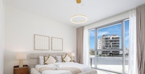 A modern hotel room with a large window, a neatly made bed, and a view of a building under construction. - LUX District One Lagoon View Townhouse (Dubai)