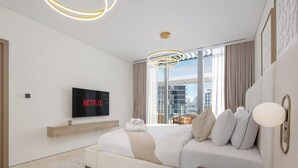 Ein modernes Hotelzimmer mit Bett, einem an der Wand montierten Fernseher, der 'NETFLIX' anzeigt, einem Fenster mit Vorhängen und Blick auf die Stadt.