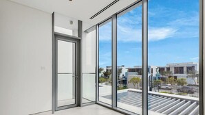 Ein modernes Interieur mit großen Fenstern, einer Tür und Blick auf die Stadtlandschaft.
