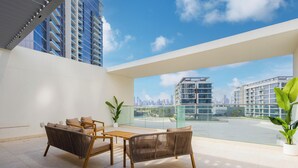Ein moderner Balkon mit Blick auf eine Stadtlandschaft, ausgestattet mit Korbstühlen und einem kleinen Tisch.
