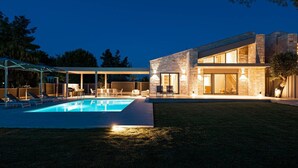 Una casa moderna con piscina, mobiliario exterior y fachada de piedra.