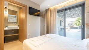 Una habitación de hotel moderna con una cama grande, ducha integrada y puerta de cristal corredera al exterior.