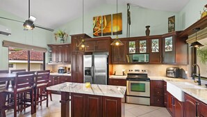 Una cucina moderna con mobili in legno scuro, elettrodomestici in acciaio inossidabile e un'isola in marmo.