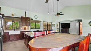 Un'ampia cucina con un'isola grande, un'area pranzo con un tavolo rotondo e una TV nel soggiorno.