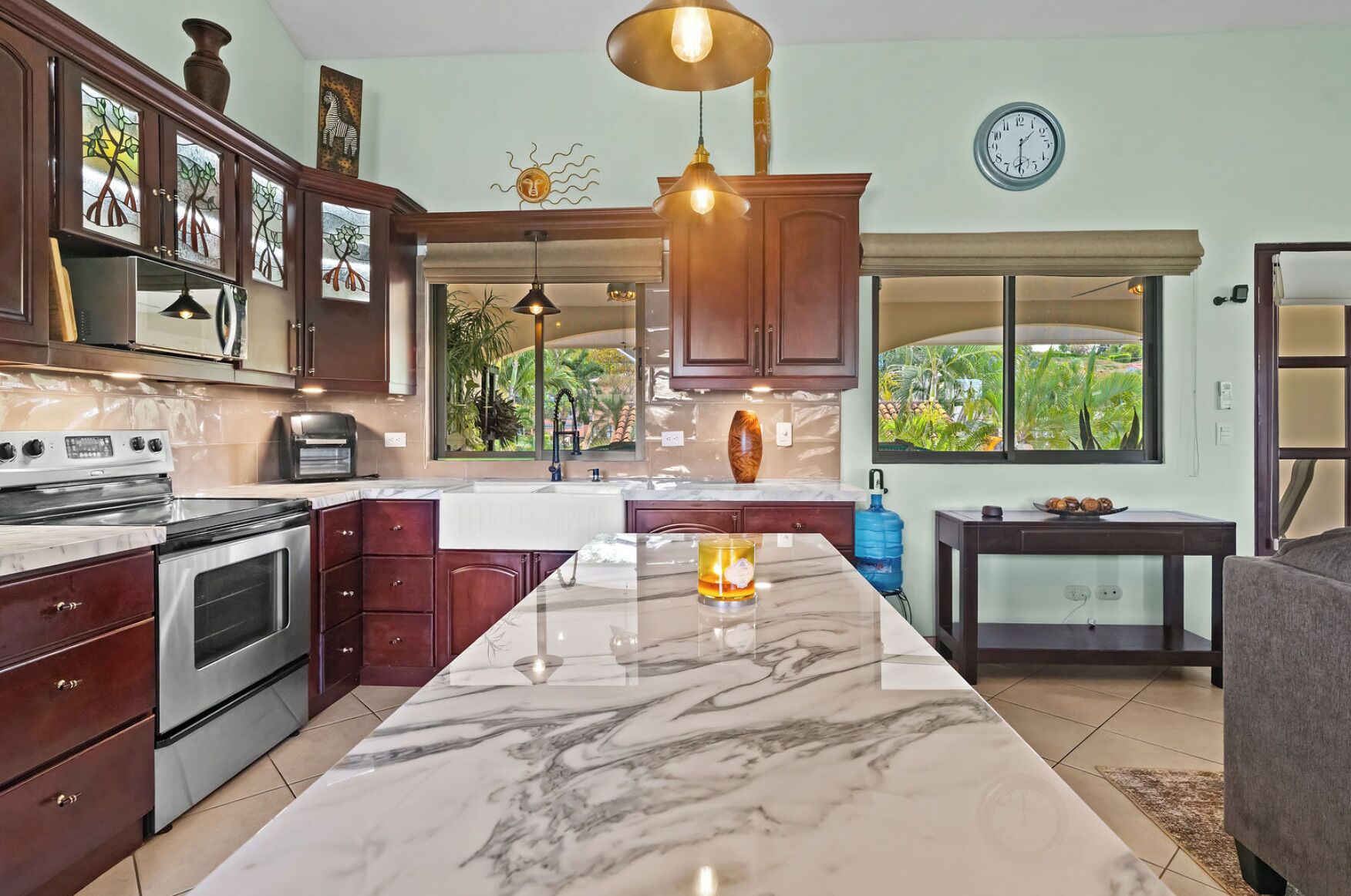 A kitchen with a large marble island, stainless steel appliances, and wooden cabinets.