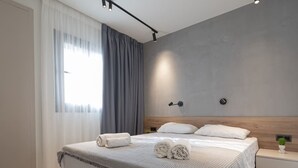 Una habitación de hotel moderna con una cama grande, cortinas grises y un diseño minimalista.