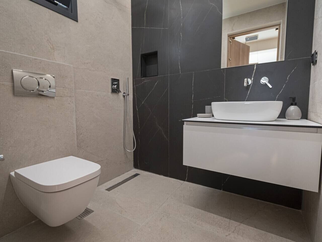 Et moderne badeværelse med toilet, håndvask og bruser.