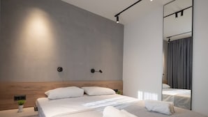A modern hotel room with a large bed, bedside tables, a mirror, and a neutral color scheme. - Theano Sea Suite 3 by Travel Pro Services (Portaria)