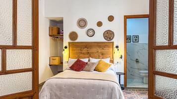 A bedroom with a wooden headboard, a bed with white bedding, and decorative wall hangings.