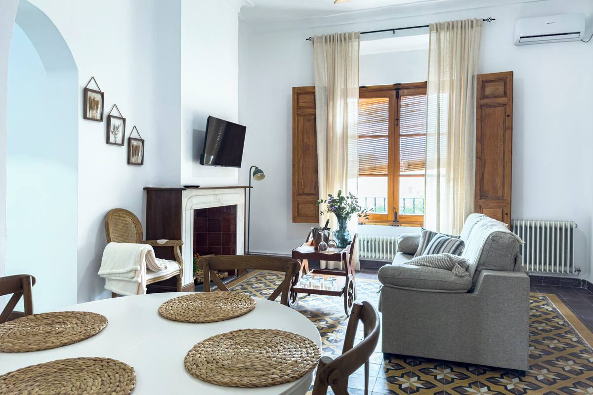 Un salon avec une cheminée, un téléviseur, un canapé et une table à manger avec des sets de table.