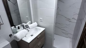 A bathroom with a white sink, mirror, and toilet.