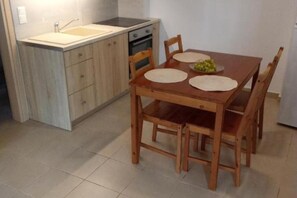 A compact kitchen with a sink, stove, and wooden dining table with chairs.