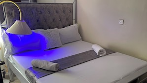 A neatly made bed with a grey headboard, a white pillow, a rolled white towel, and a grey blanket. - Paradise Villa just outside Paradise/Karura forest for Nature visit,walks & more (Kiambu)