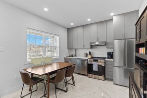 Une cuisine moderne avec des meubles gris, des appareils en acier inoxydable et un sol en marbre.
